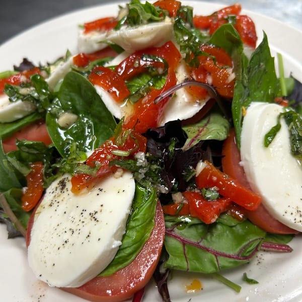 A vibrant Bella Pasta Caprese salad with fresh mozzarella, tomatoes, basil, and roasted red peppers.