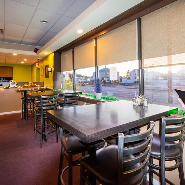 Bella Pasta's dining room with high-top tables, bar stools, and large windows overlooking a street.